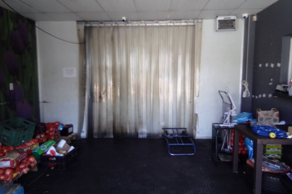 A functional utility or storage area featuring a plastic strip curtain entrance, suspended ceiling, and wall-mounted air conditioning unit.