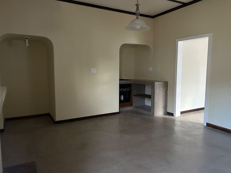 A minimalist kitchen area featuring a concrete countertop, built-in oven, and distinctive arched alcoves, finished with smooth concrete flooring.
