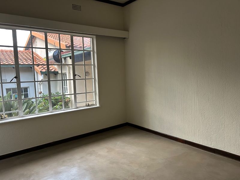 An empty bedroom featuring concrete flooring, steel-framed windows, and neutral walls, providing a blank canvas for interior design.