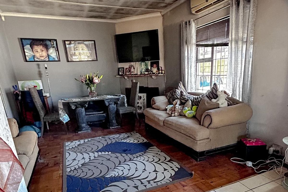 Living room featuring parquet and tiled flooring with an installed air conditioning unit. The ceiling shows significant signs of water damage or staining.