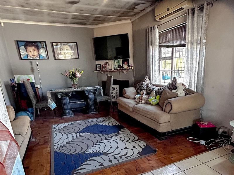 Living room featuring parquet and tiled flooring with an installed air conditioning unit. The ceiling shows significant signs of water damage or staining.