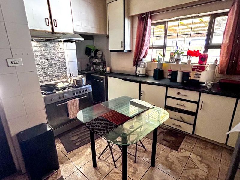 A dated kitchen featuring built-in cabinetry, a freestanding stove with extractor fan, and tiled flooring, requiring significant ceiling repairs and cosmetic updates.