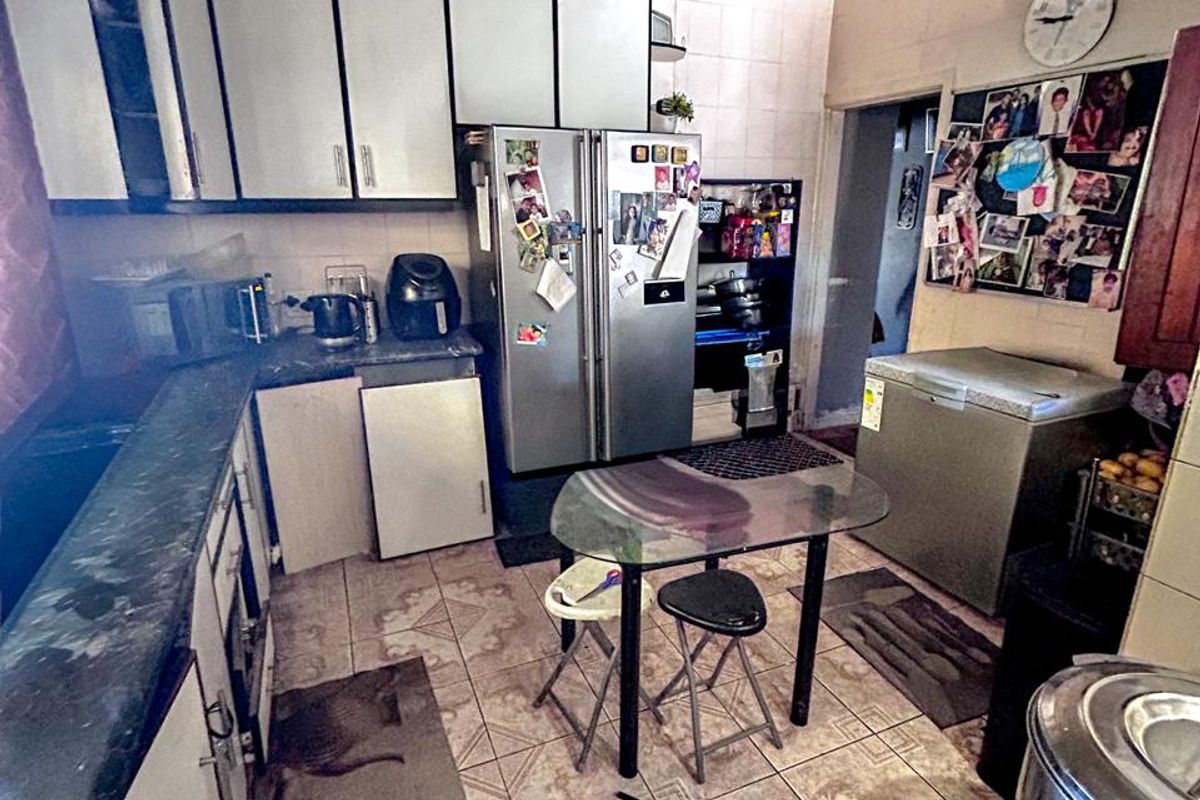 A dated kitchen featuring built-in cabinetry and tiled flooring, currently showing significant signs of wear and requiring cosmetic updates.