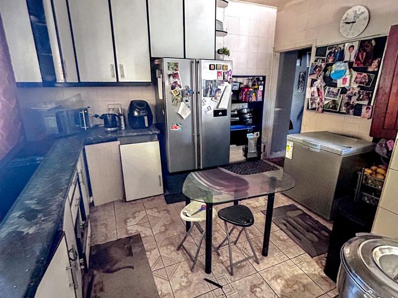 A dated kitchen featuring built-in cabinetry and tiled flooring, currently showing significant signs of wear and requiring cosmetic updates.