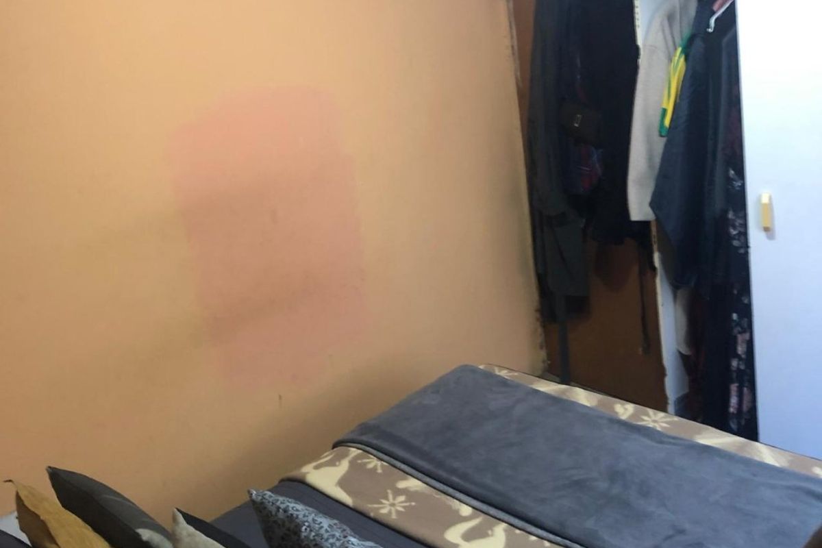 A bedroom featuring a built-in wardrobe and plain wall finishes, currently showing signs of wear and paint discoloration.