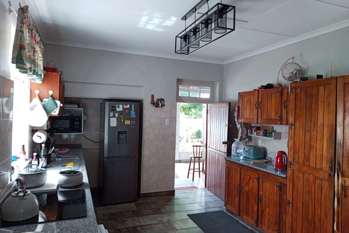 A functional kitchen featuring wooden cabinetry, granite countertops, and tiled flooring, with direct access to an outdoor area.
