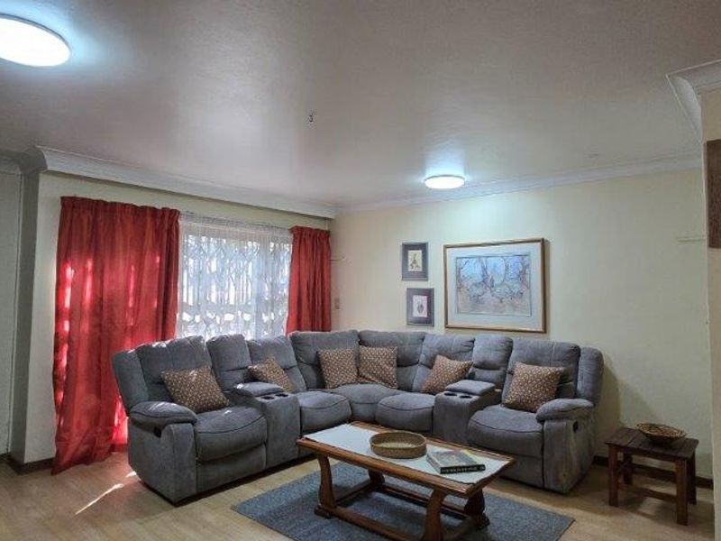 A comfortable living room featuring laminate flooring, coving, and flush mount ceiling lights, providing a functional and inviting space for relaxation.