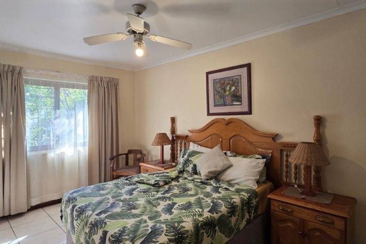 A bedroom featuring tiled flooring, a ceiling fan, and a window with curtains.