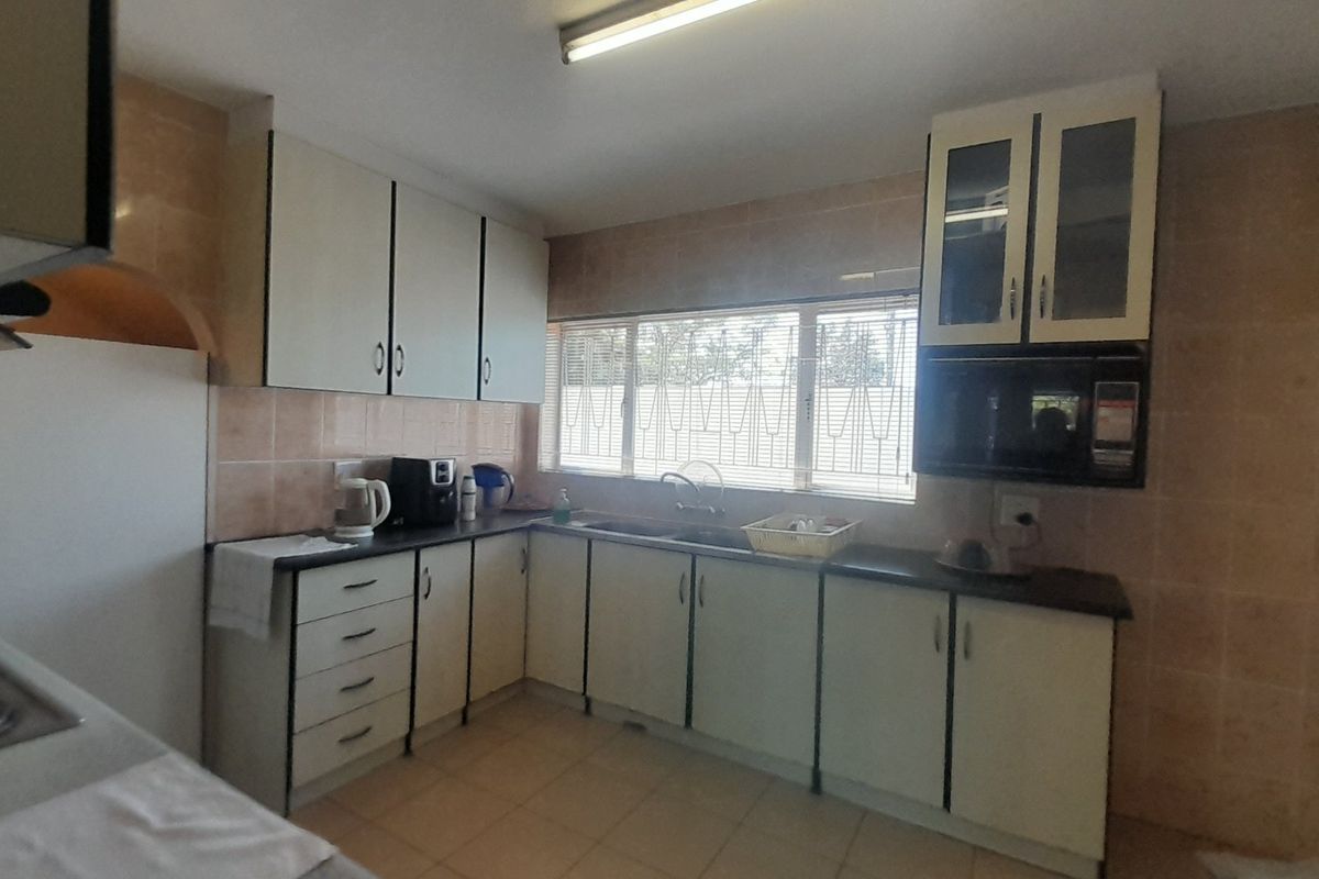 A functional kitchen featuring built-in cabinetry, laminate countertops, a double basin sink, and tiled splashbacks, offering a practical layout with potential for modernization.