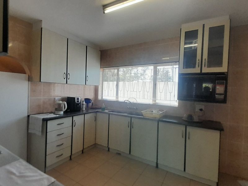 A functional kitchen featuring built-in cabinetry, laminate countertops, a double basin sink, and tiled splashbacks, offering a practical layout with potential for modernization.