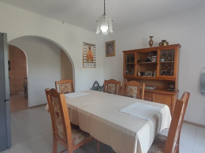 A dining room featuring tiled flooring, a central pendant light fixture, and an arched entryway leading to an adjacent space.