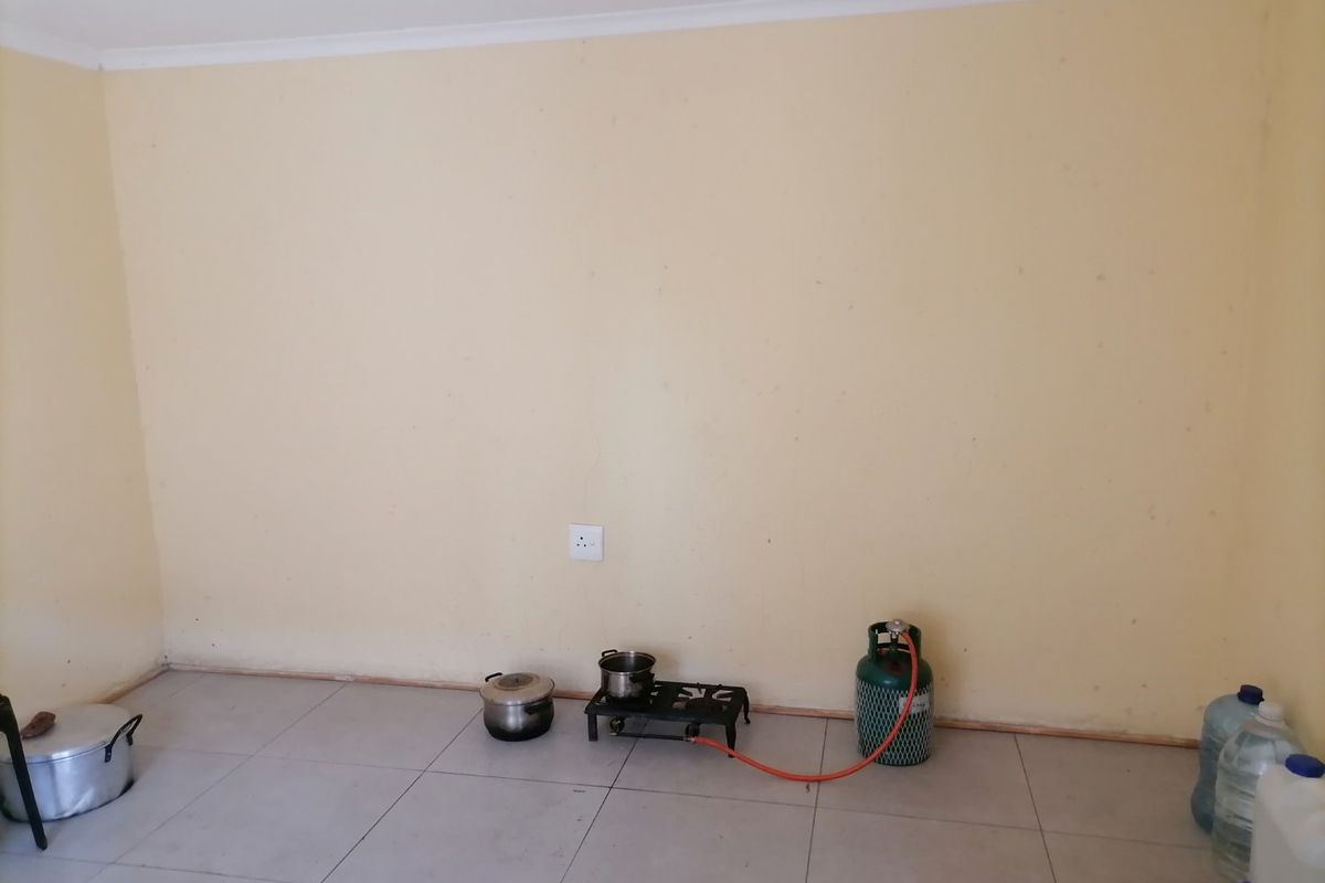 An empty kitchen area featuring tiled flooring and plain walls, providing a blank canvas for custom cabinetry and appliance installation.