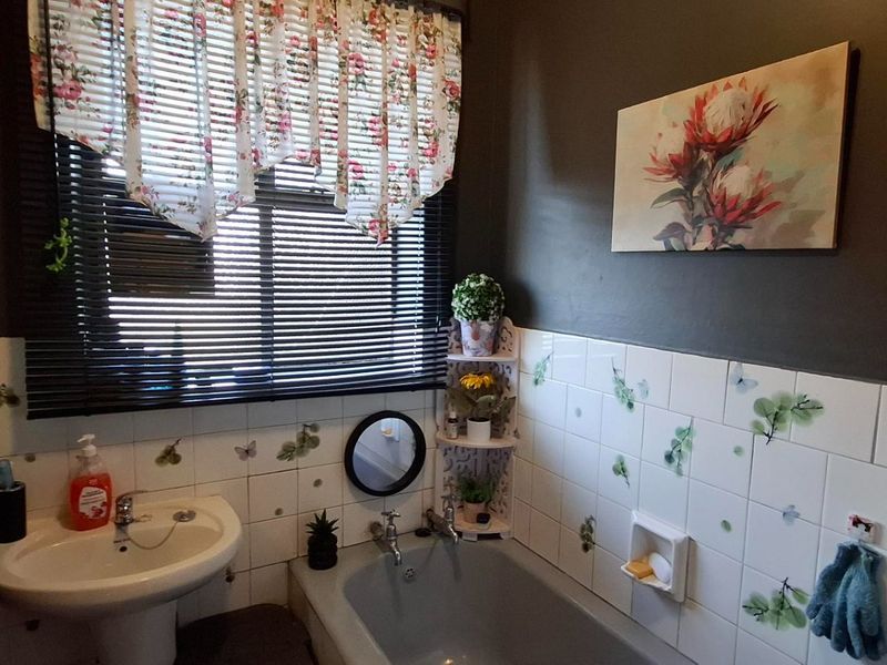 A functional bathroom featuring a pedestal basin, built-in bathtub, and tiled wall finishes with decorative accents.