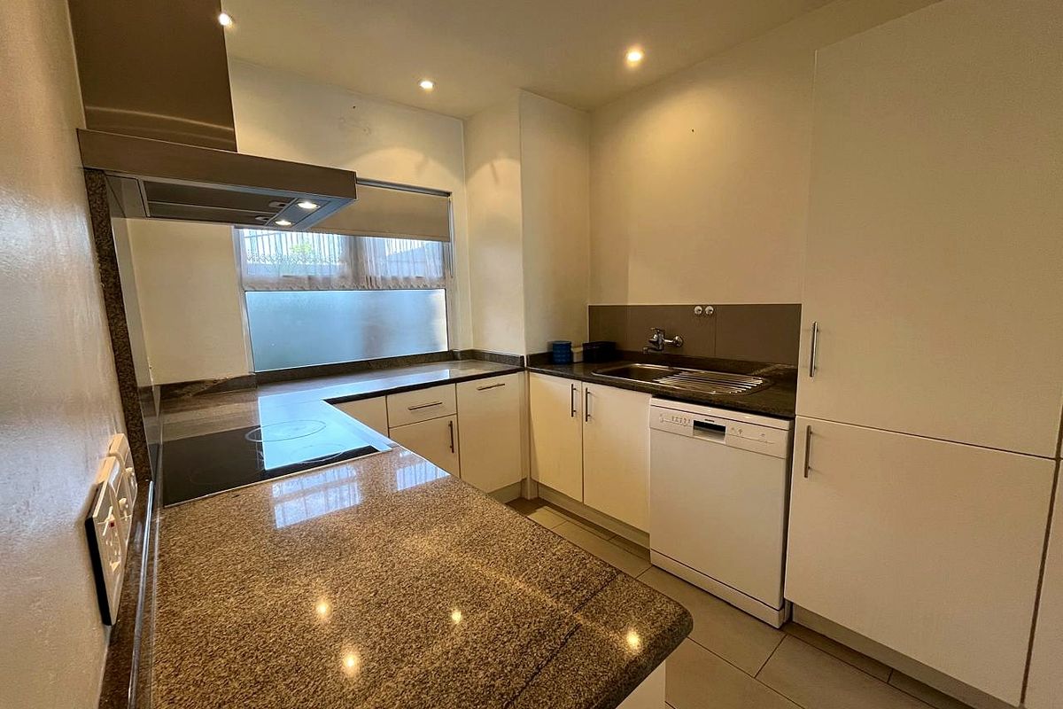 A functional kitchen featuring granite countertops, integrated appliances, and ample built-in cabinetry, illuminated by recessed downlights.