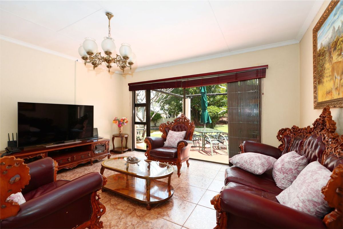 A living room featuring tiled flooring, a decorative chandelier, and large sliding glass doors providing direct access to the outdoor patio area.