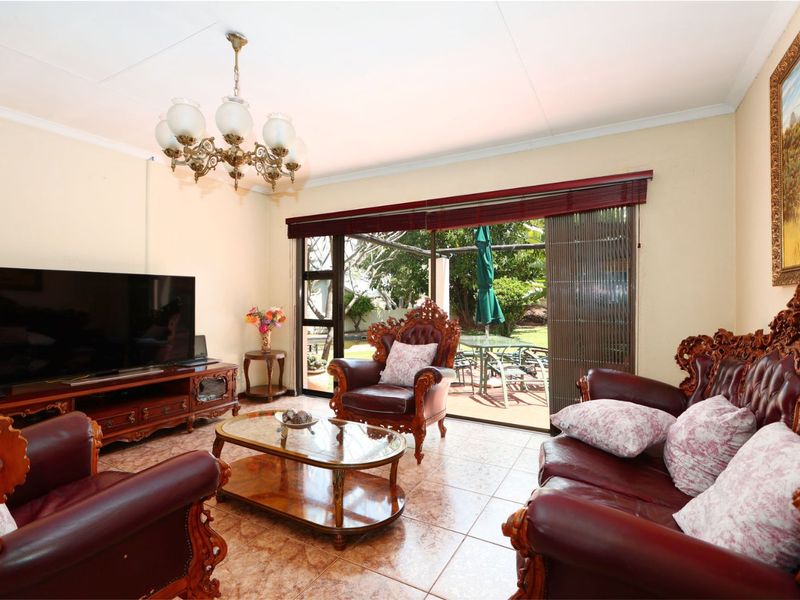 A living room featuring tiled flooring, a decorative chandelier, and large sliding glass doors providing direct access to the outdoor patio area.