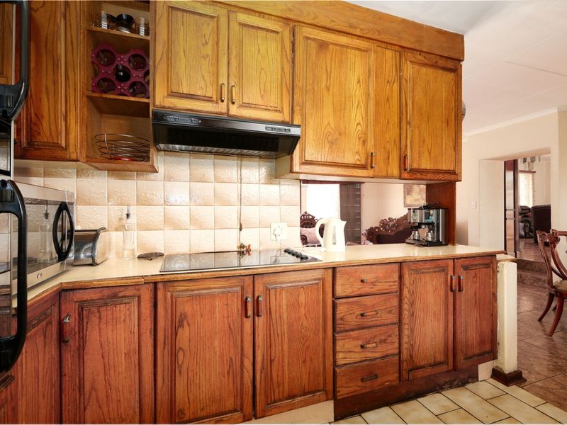 A functional kitchen featuring traditional wooden cabinetry, a ceramic tile backsplash, and integrated cooking appliances, offering a classic layout with potential for modernization.