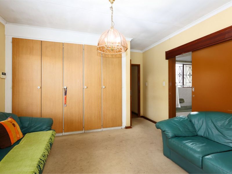 A bedroom featuring built-in wooden cupboards, carpeted flooring, and a sliding door leading to an adjacent bathroom area.
