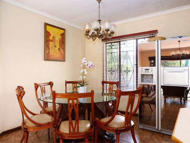 A dining room featuring tiled flooring, a decorative chandelier, and window blinds with security gates.