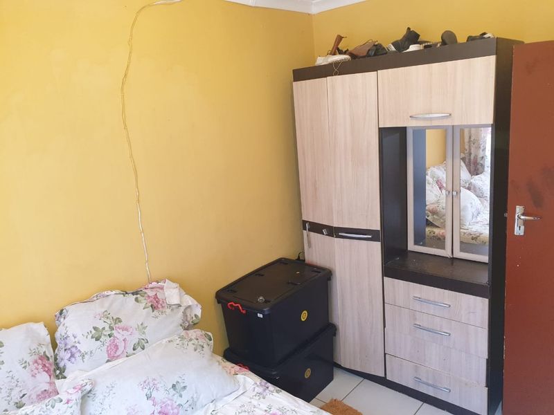 A bedroom featuring tiled flooring and yellow painted walls with visible surface-mounted electrical wiring.