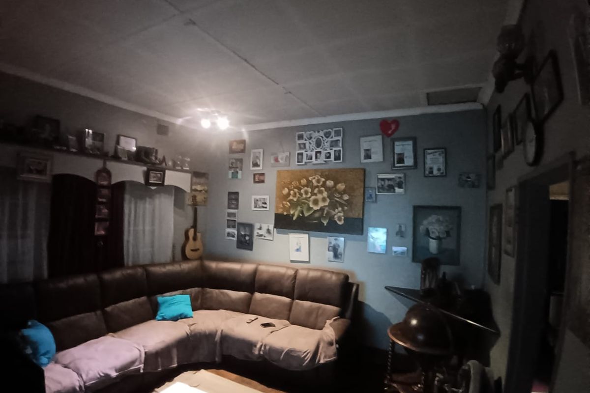 A living room featuring a corner sofa layout with ceiling tile finishes and recessed lighting, providing a functional space for relaxation.