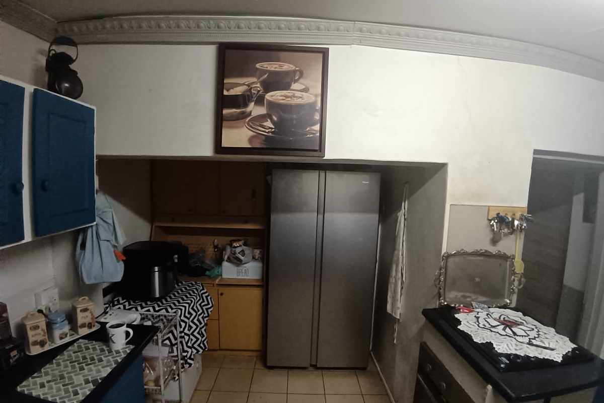 A dated kitchen featuring built-in cabinetry, tiled flooring, and an integrated oven, currently showing signs of wear and requiring cosmetic updates.