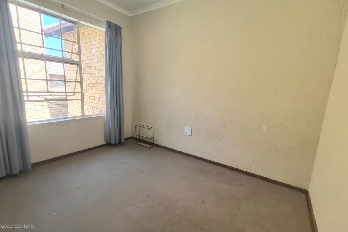 A vacant bedroom featuring carpeted flooring, a large window providing natural light, and neutral wall finishes, ready for personalization.
