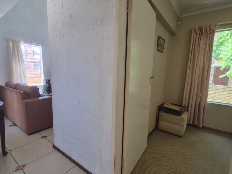 Open plan living area featuring a mix of tiled and carpeted flooring, with a central partition wall and access to natural light.