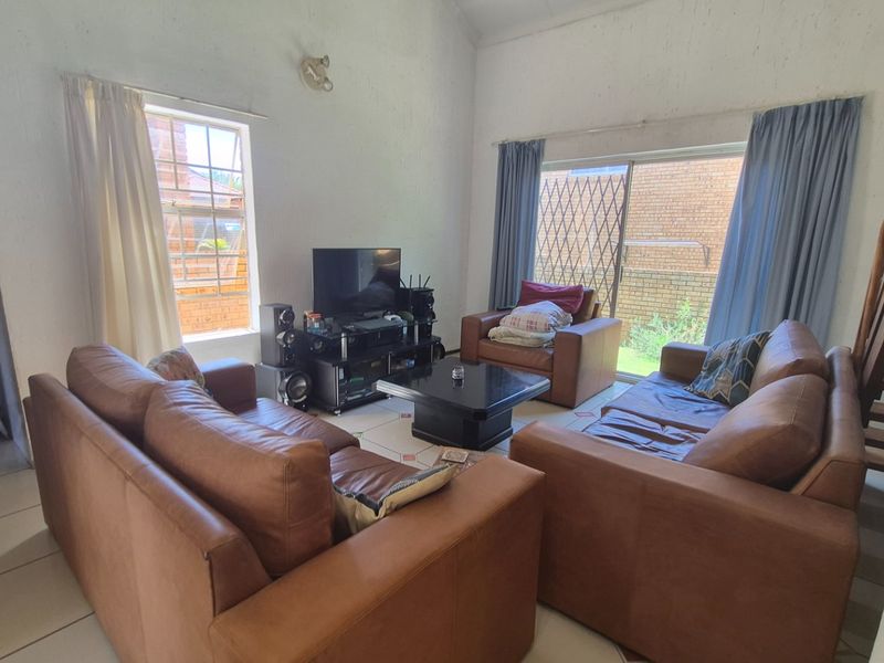 Spacious living room featuring tiled flooring, a vaulted ceiling, and a sliding glass door providing access to the exterior.