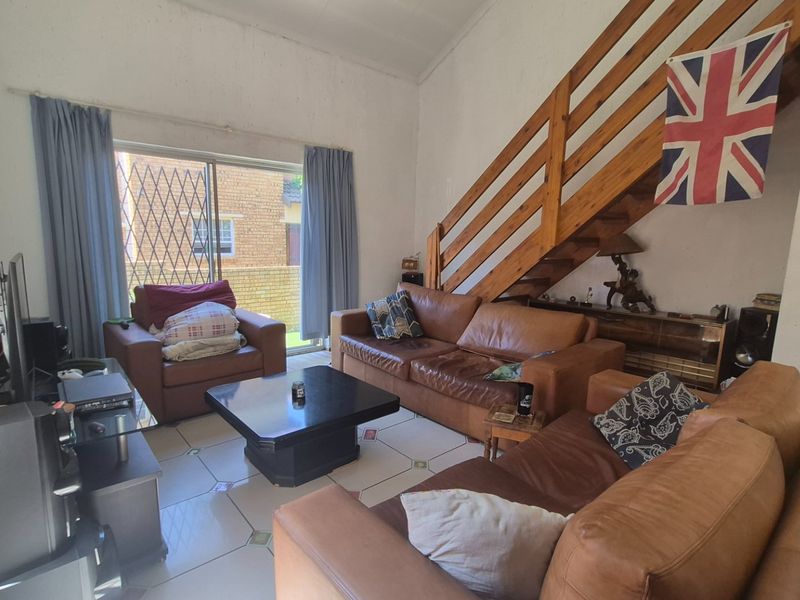 Spacious living room featuring a wooden staircase, tiled flooring, and a sliding glass door providing access to the exterior.