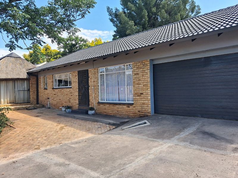 Front elevation of a single-story brick house featuring a tiled roof, integrated garage, and paved driveway area.