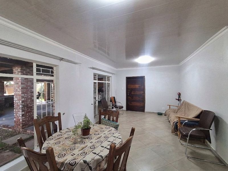 Spacious open-plan living and dining area featuring tiled flooring, a glossy ceiling with crown molding, and direct access to the outdoor patio.