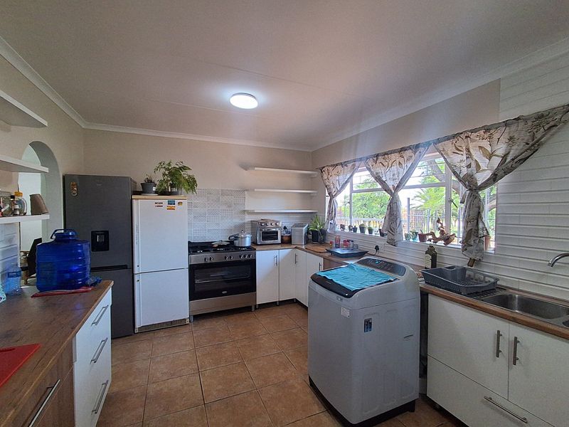 A functional kitchen featuring tiled flooring, timber countertops, built-in cabinetry, and a gas stove with oven, offering a practical layout for daily use.