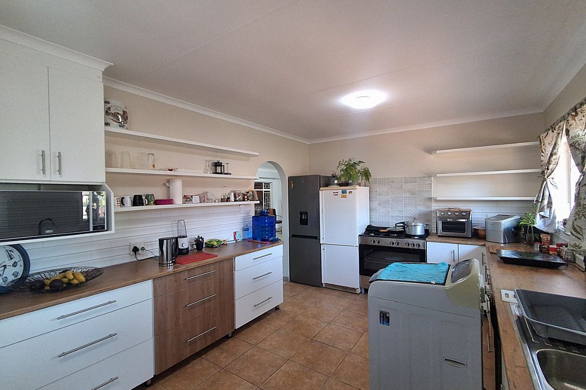 A functional kitchen featuring wooden countertops, white and wood-tone cabinetry, open shelving, and built-in cooking appliances with tiled flooring.
