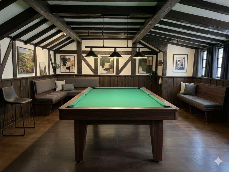 A well-appointed games room featuring exposed timber ceiling beams, dark wood wall paneling, and integrated bench seating, creating a sophisticated and cozy atmosphere.