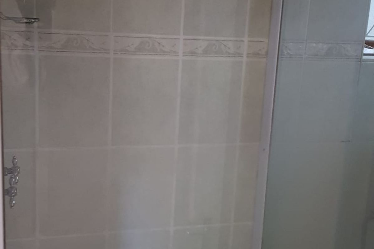 A functional shower enclosure featuring tiled walls and standard shower fixtures, presenting a clean and neutral space ready for potential updates.