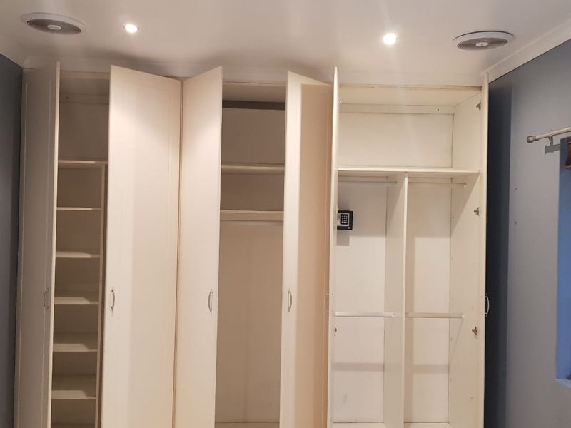 A bedroom featuring extensive built-in cabinetry with integrated shelving, hanging space, and a built-in safe, complemented by recessed lighting and ceiling ventilation.