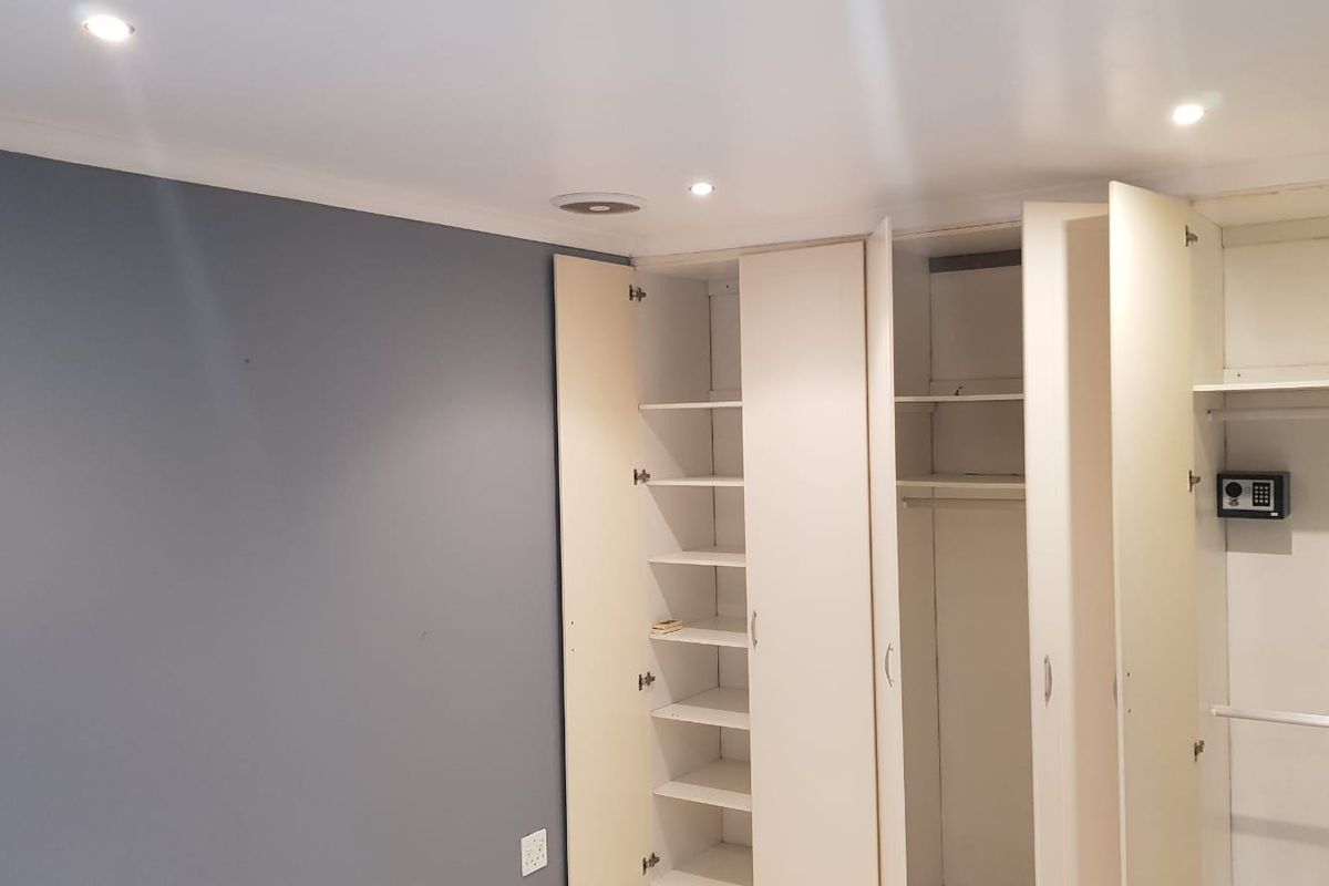 A bedroom featuring extensive built-in cabinetry with shelving and hanging space, including an integrated wall safe and recessed ceiling lighting.