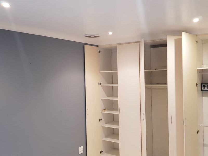 A bedroom featuring extensive built-in cabinetry with shelving and hanging space, including an integrated wall safe and recessed ceiling lighting.