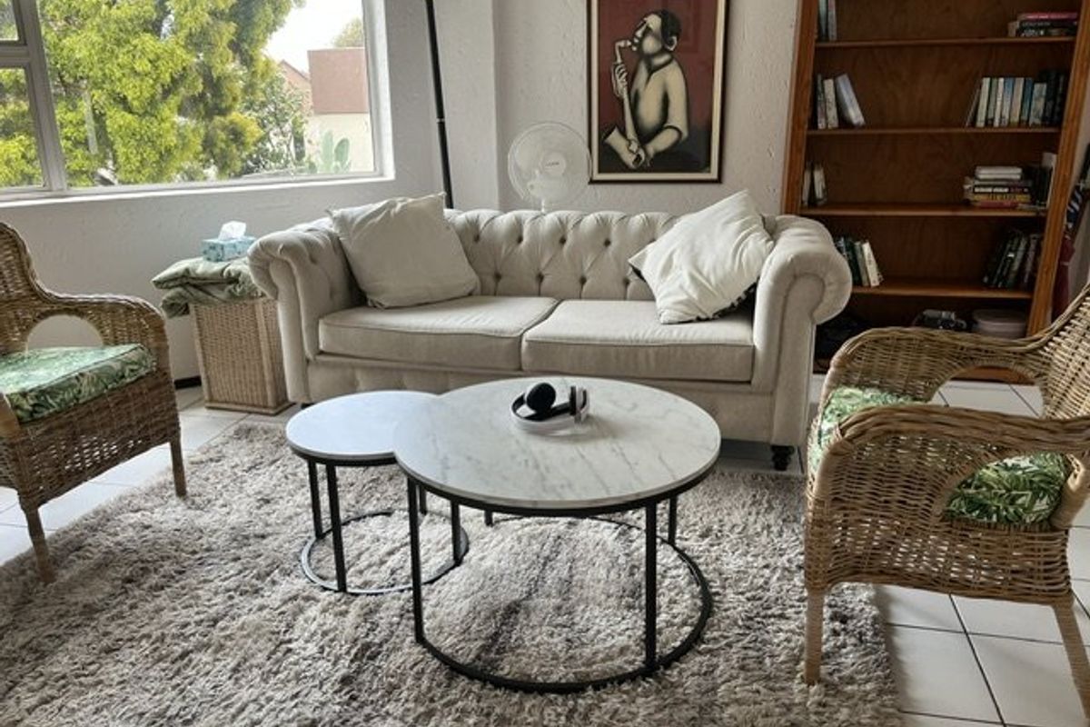 A bright living room featuring large windows that provide natural light and neutral tiled flooring throughout the space.