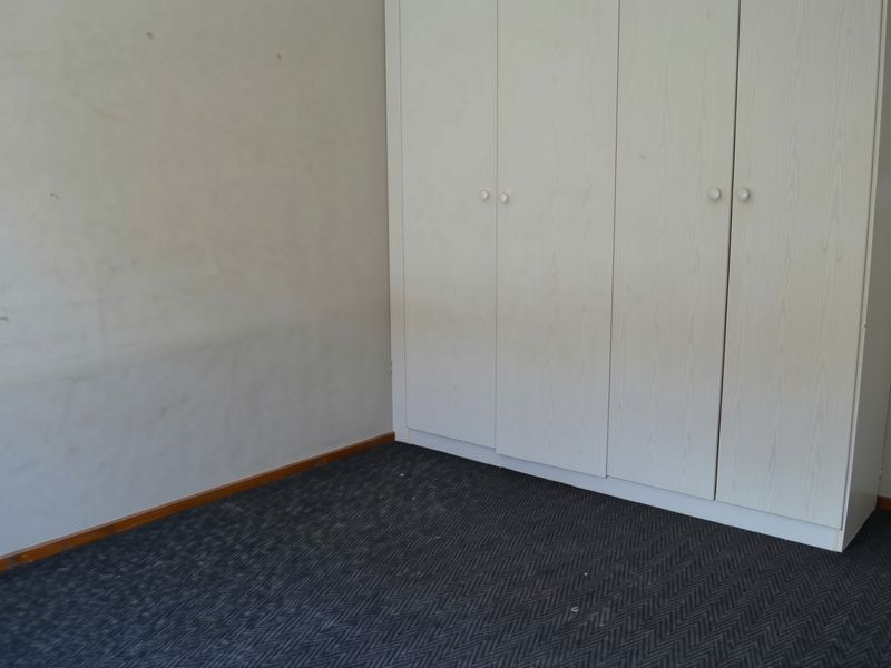 An empty bedroom featuring built-in wardrobes, carpet flooring, and neutral walls, offering a blank canvas for personalization.