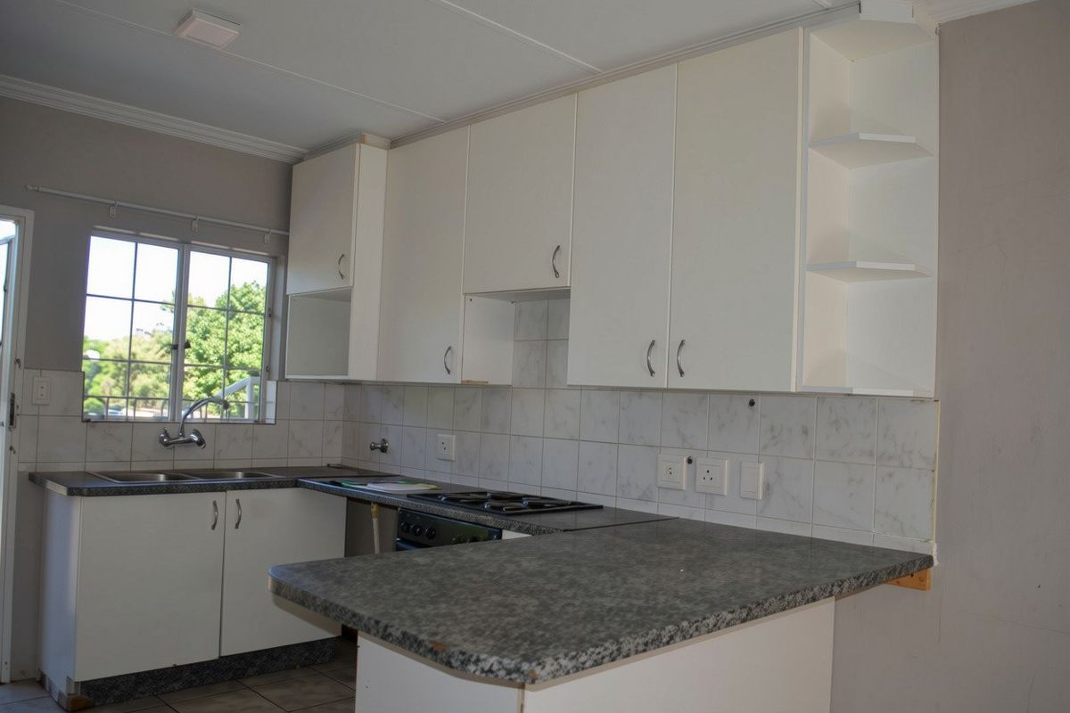 A functional kitchen featuring white cabinetry, laminate countertops, a built-in gas hob, and a tiled backsplash, offering a clean and practical workspace.