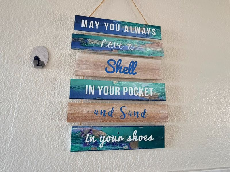 A close-up view of a decorative wall hanging featuring coastal-themed text.