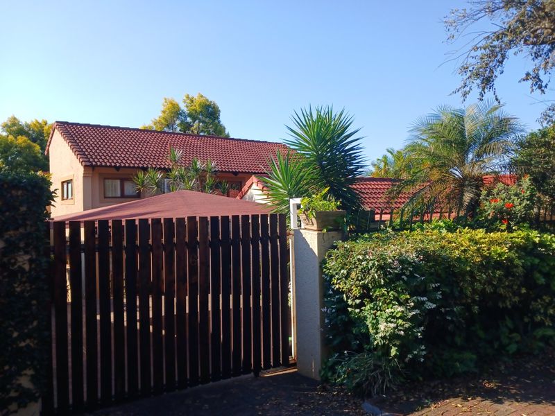 A view of the property entrance featuring a timber slat gate, masonry pillar, and a well-maintained tiled roof structure.