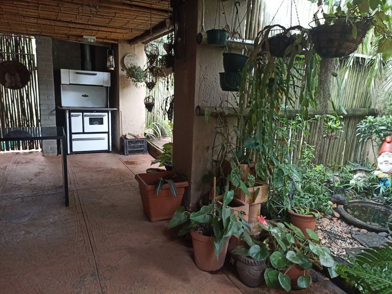 Covered outdoor patio area featuring a built-in wood-burning stove, concrete flooring, and rustic bamboo screening, ideal for relaxed outdoor entertaining.