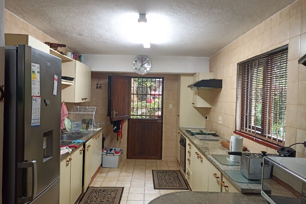 A functional kitchen featuring granite countertops, built-in cabinetry, and a stable door leading to the exterior, offering a practical layout with dated finishes.