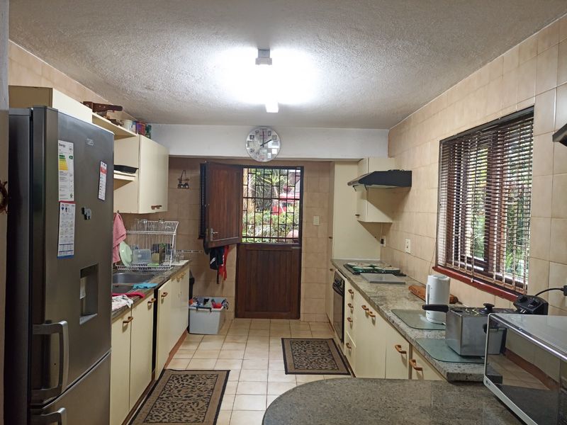 A functional kitchen featuring granite countertops, built-in cabinetry, and a stable door leading to the exterior, offering a practical layout with dated finishes.