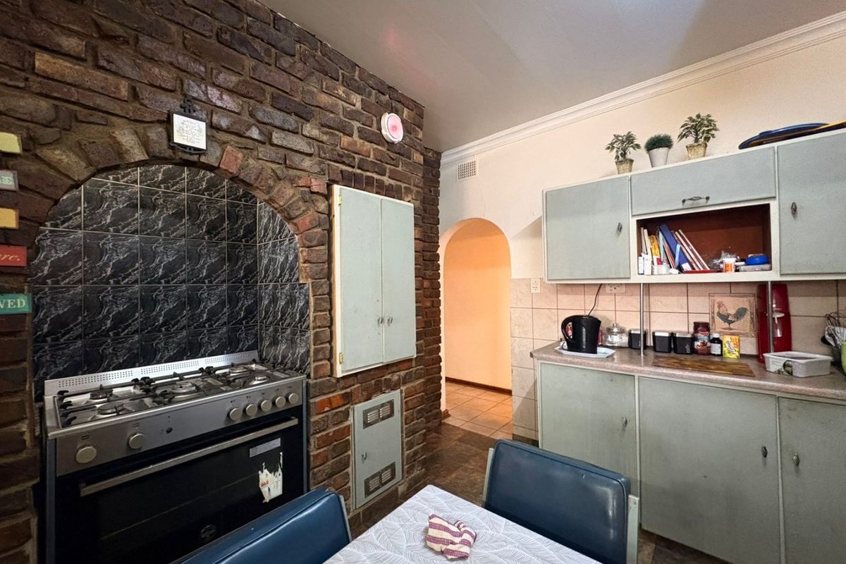 Kitchen featuring a rustic exposed brick feature wall with a built-in oven and gas hob, complemented by traditional cabinetry and tiled splashbacks.