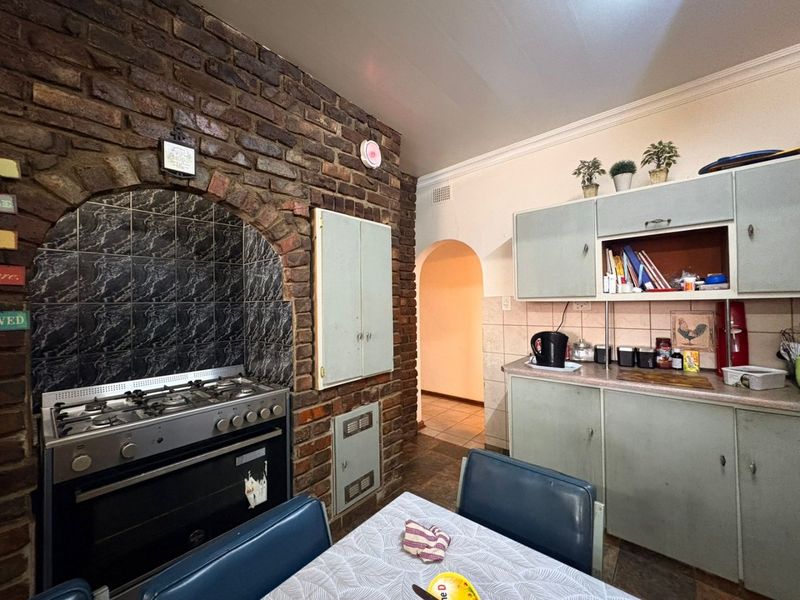 Kitchen featuring a rustic exposed brick feature wall with a built-in oven and gas hob, complemented by traditional cabinetry and tiled splashbacks.