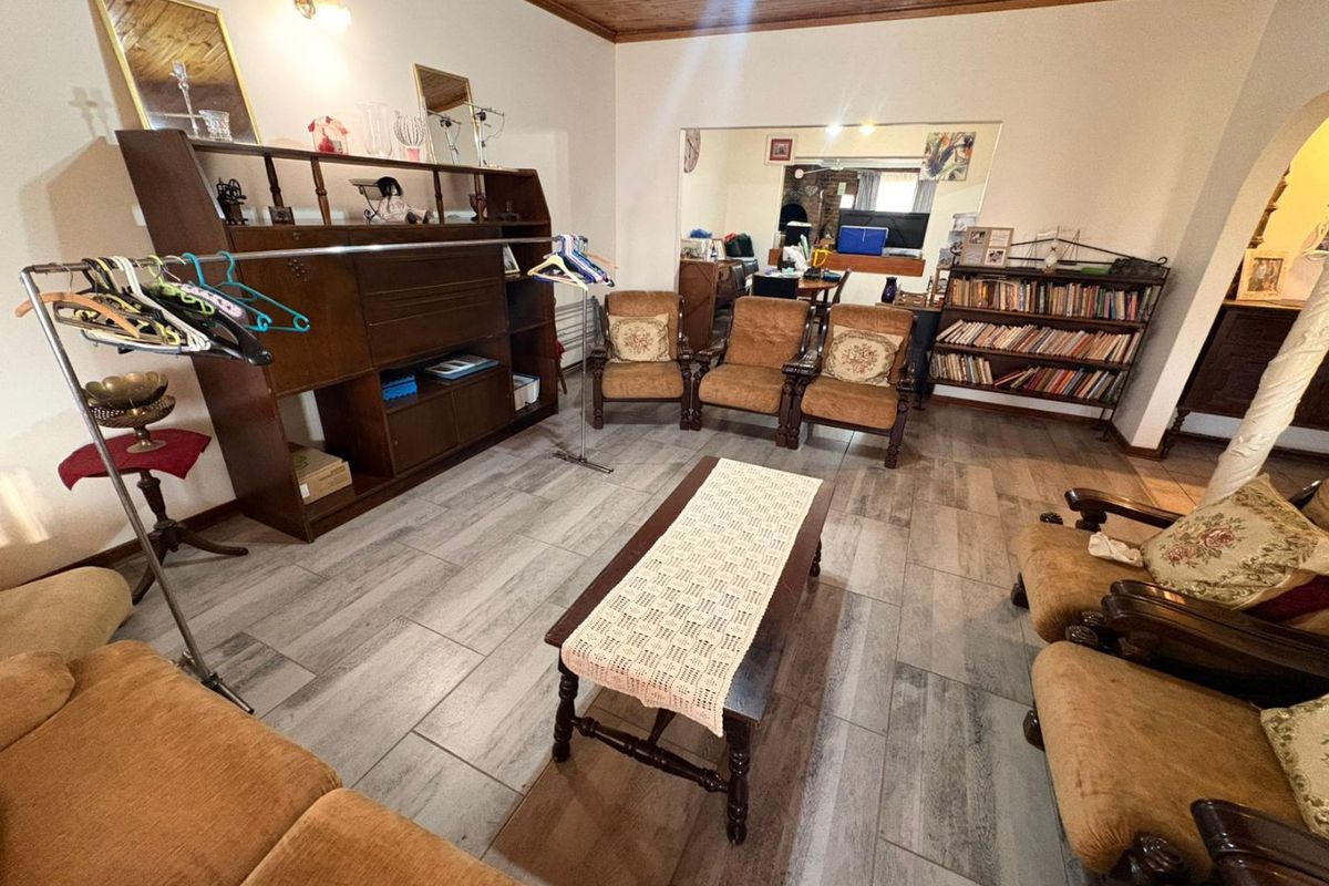 A spacious living room featuring timber ceiling finishes and modern wood-look floor tiles, providing a neutral foundation for interior updates.